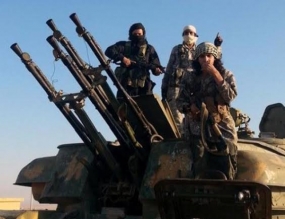 This August 7, 2014 image posted by the Raqqa Media Centre shows fighters from the Islamic State group on top of a military vehicle with anti-aircraft guns in Syria’s Raqqa Province.